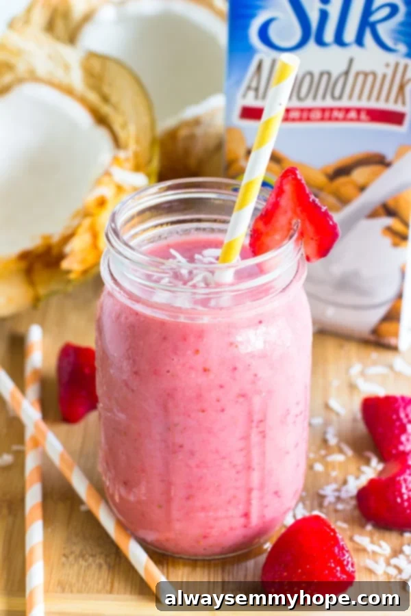 A strawberry coconut smoothie in a mason jar with a yellow straw, evoking tropical vibes.