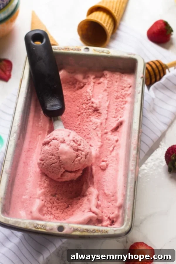 Strawberry Coconut Ice Cream in a silver tub, showcasing its creamy, refreshing texture.