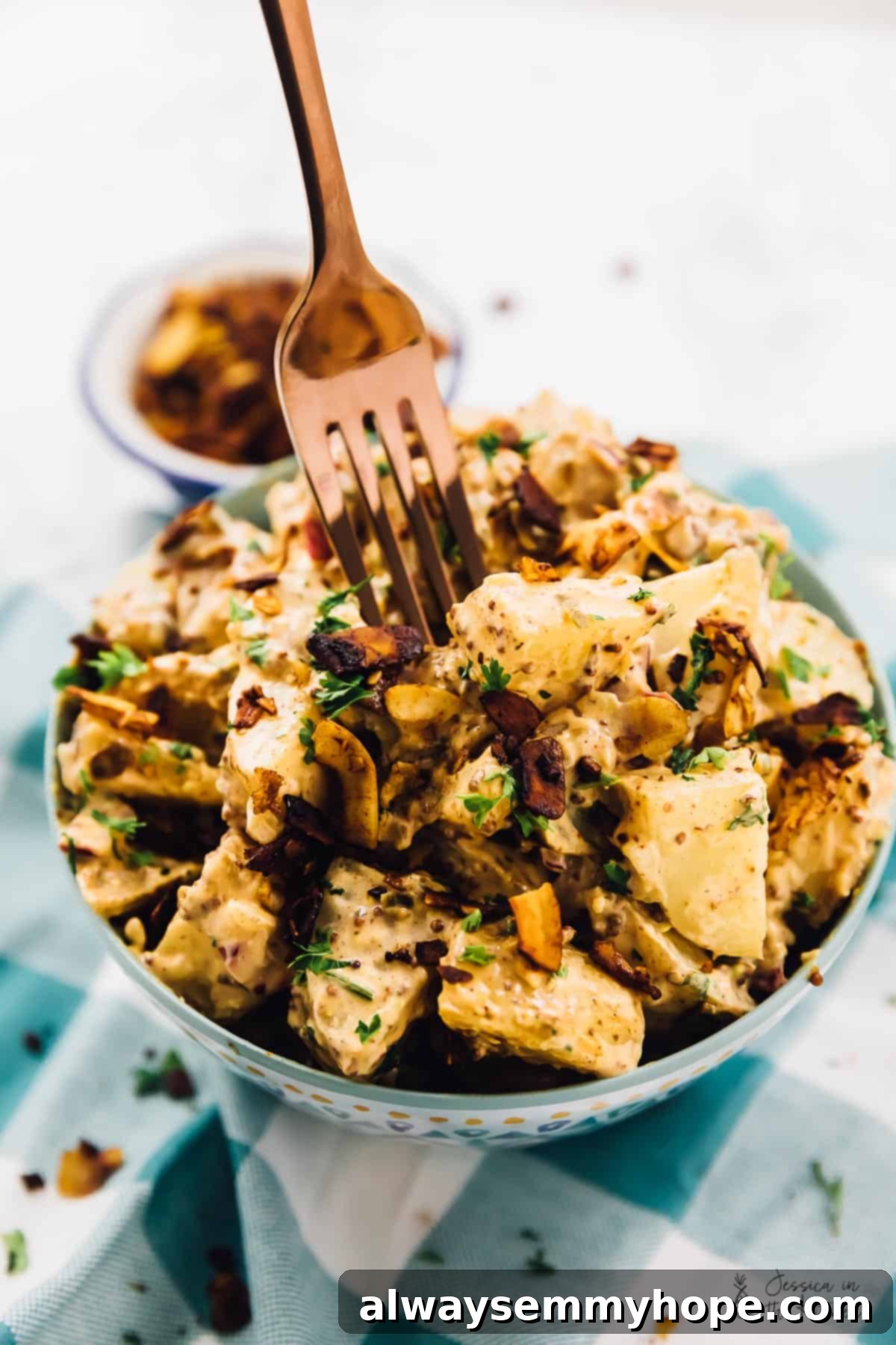 A fork digging into a bowl of loaded vegan potato salad. 
