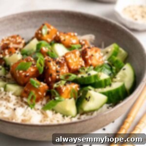 Bowl filled with rice, cucumbers, and orange tofu