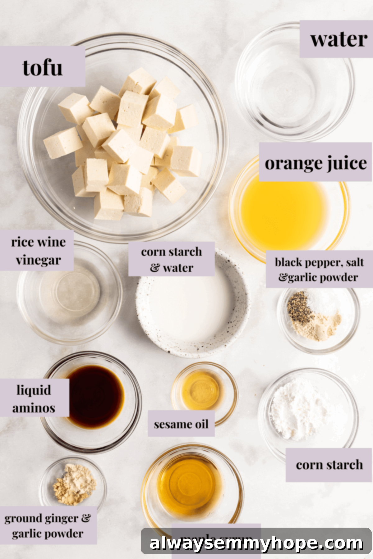An overhead view showcasing the various fresh and pantry ingredients laid out for making air fryer orange tofu, including tofu, oranges, spices, and sauces.