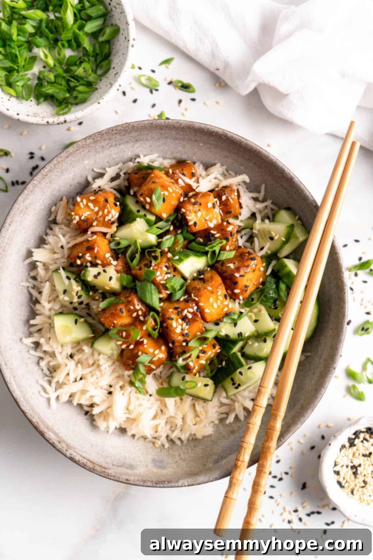 A close-up overhead shot of a single bowl of air fryer orange tofu with rice and cucumber, perfectly plated and ready to be enjoyed.