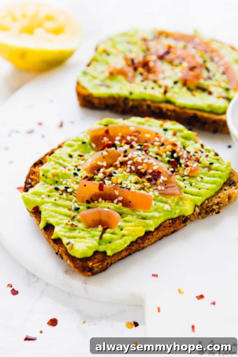 Two perfectly prepared slices of avocado toast garnished with fresh toppings, displayed on an elegant marble board for a gourmet breakfast