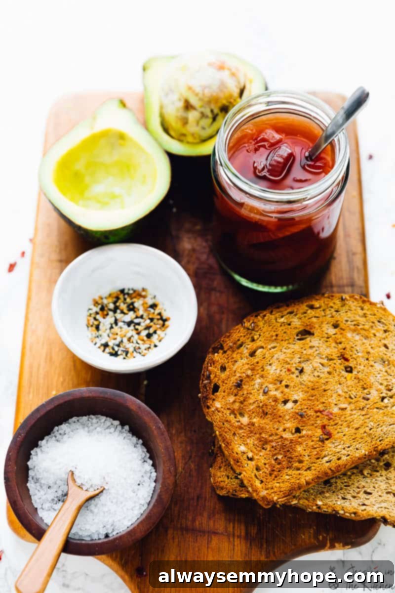 Fresh ingredients laid out for making avocado toast: wholesome bread, bright pickled onions, ripe avocado halves, savory everything bagel seasoning, and sea salt