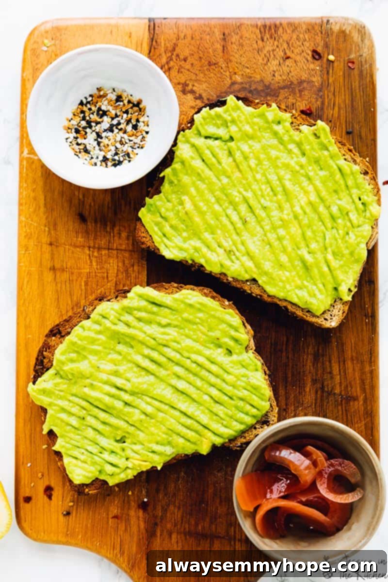 Two slices of golden-brown toast generously spread with creamy, seasoned avocado