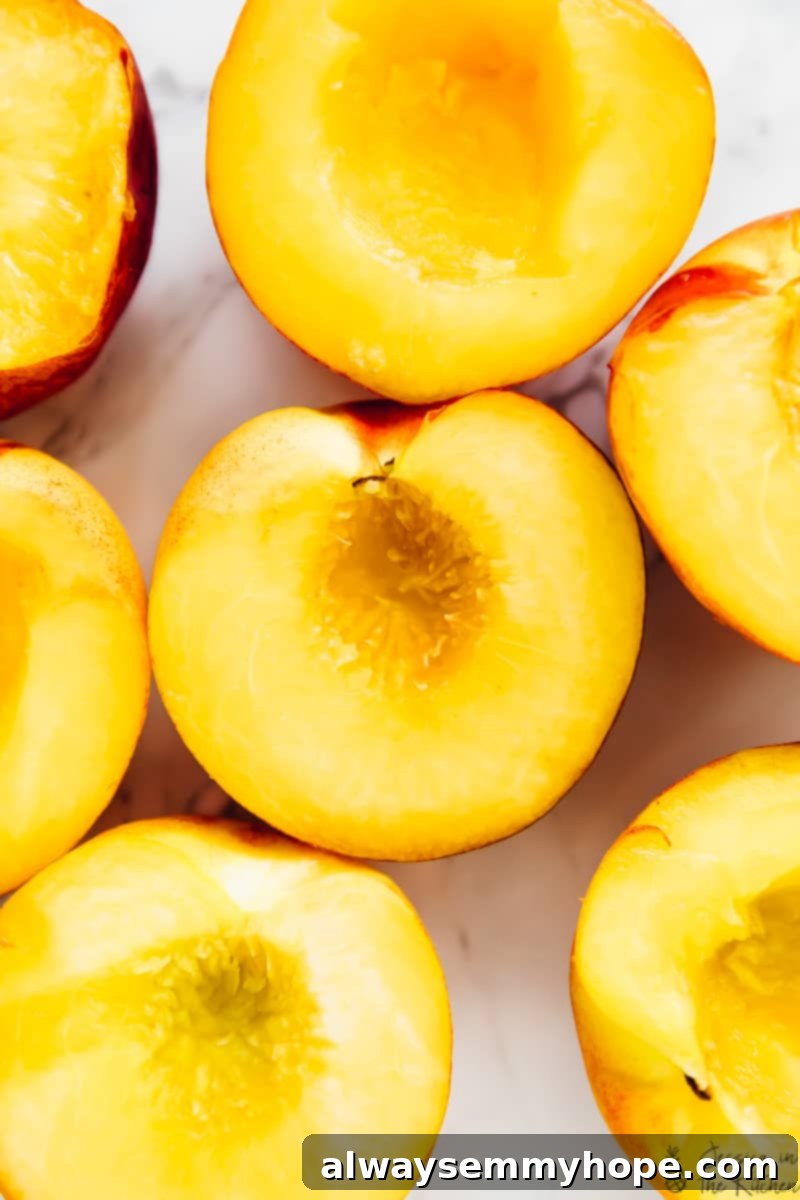 Juicy grilled peaches are sweet, smoky, and the perfect summer treat topped with vegan coconut ice cream! It takes minutes on a hot grill. Peaches cut into halves with the pits removed, ready for the grill.