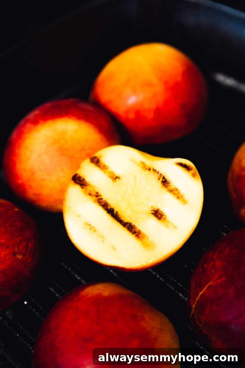 Juicy grilled peaches are sweet, smoky, and the perfect summer treat topped with vegan coconut ice cream! It takes minutes on a hot grill. Close up of peaches grilling, with one flipped over to reveal the grill marks.