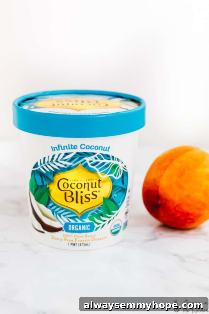 Juicy grilled peaches are sweet, smoky, and the perfect summer treat topped with vegan coconut ice cream! It takes minutes on a hot grill. A tub of Coconut Bliss vegan ice cream next to a fresh peach.