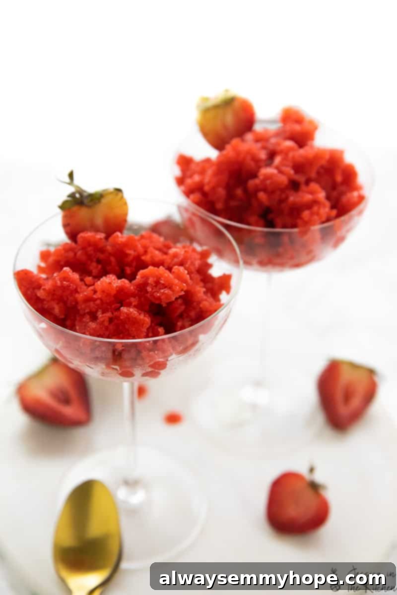 Two glasses filled with bright pink strawberry granita, garnished with fresh mint, ready to be enjoyed.