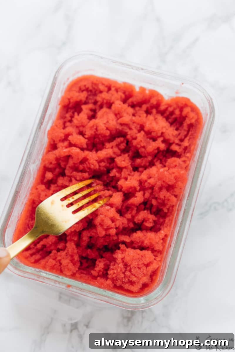 A fork scraping the surface of a pan of strawberry granita, creating beautiful icy flakes.