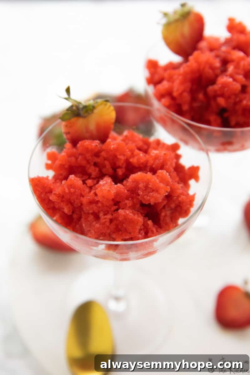 Close-up of a glass full of beautifully layered strawberry granita, highlighting its icy texture and fresh fruit appeal.