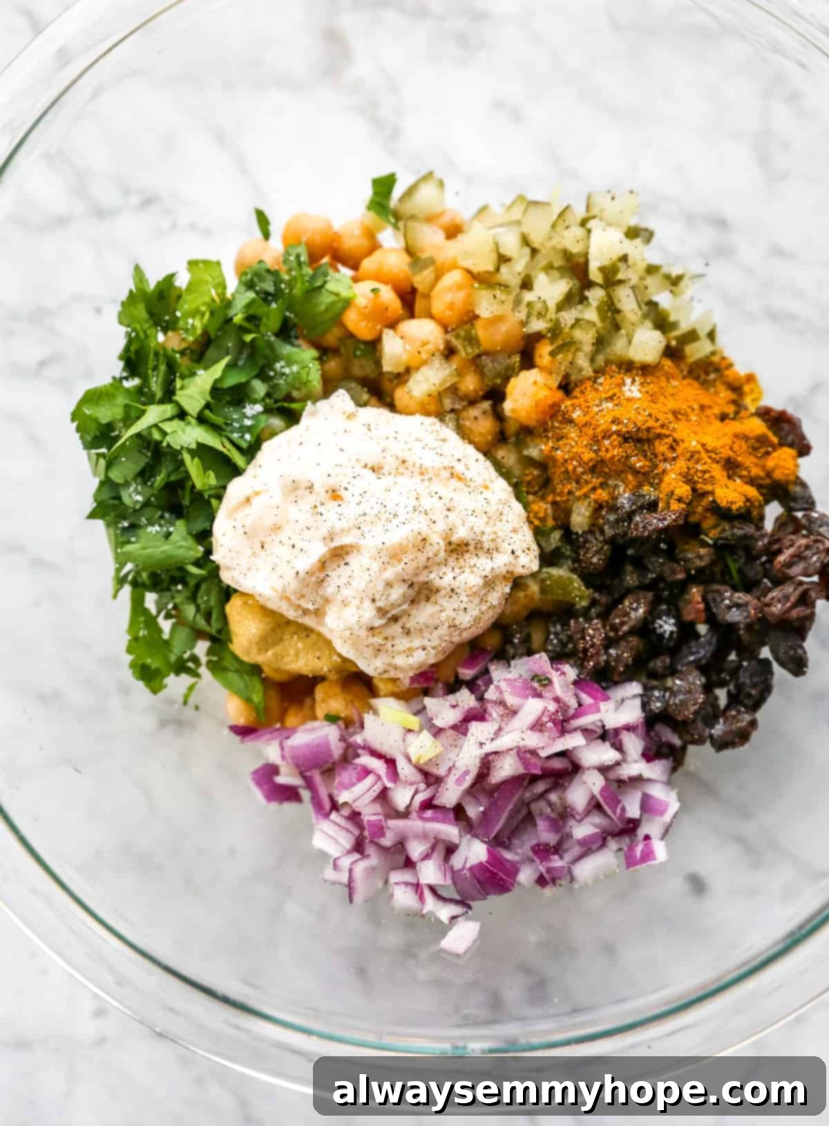 curried chickpea salad ingredients in a bowl before mixing, showcasing the vibrant colors and fresh components