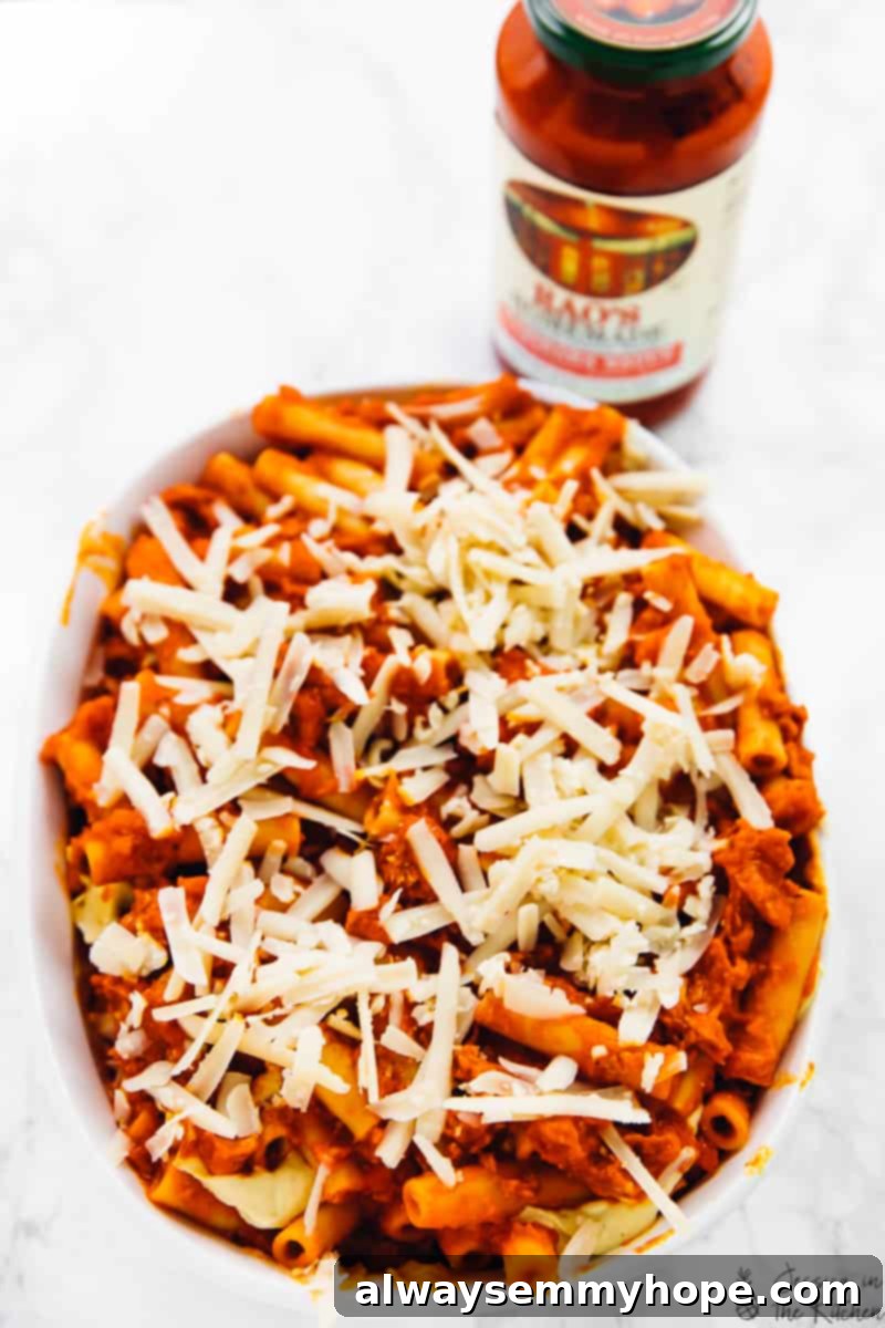 Pasta covered in vibrant tomato sauce and shredded cheese, nestled in a baking dish, ready for baking.