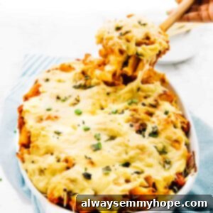 Vegan cheese baked pasta being pulled out of the serving dish with a cheese pull, highlighting the melty texture.