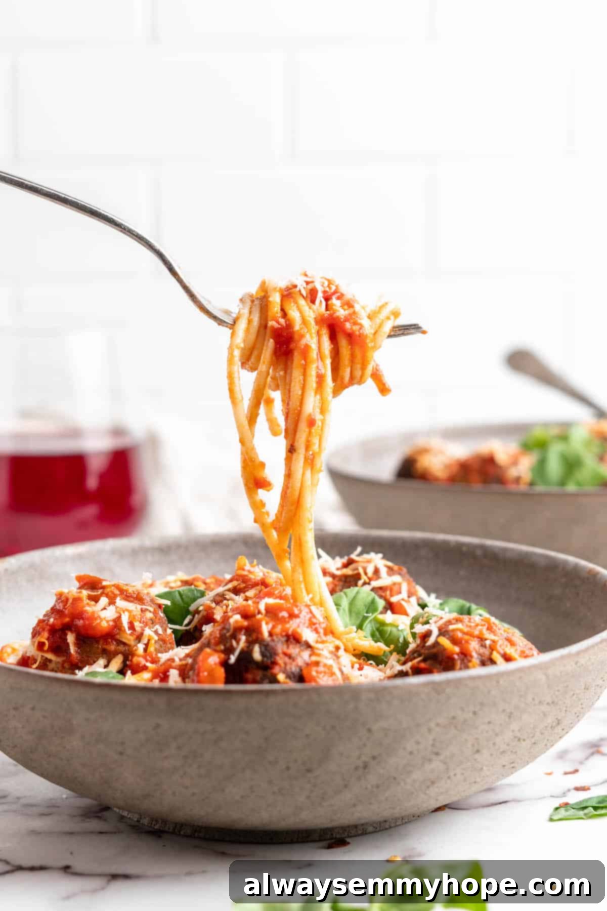 Plant-Powered Spaghetti & Meatballs 15 Spaghetti on fork held over bowl of vegan spaghetti and meatballs