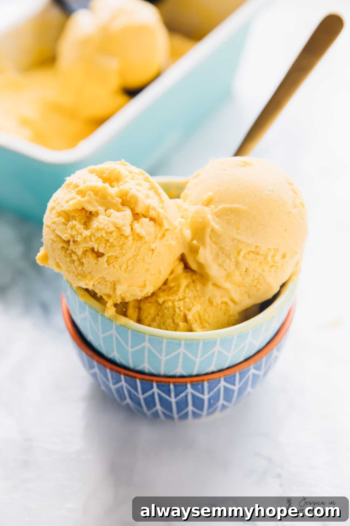 Top 15 Vegan Frozen Treats for Summer Relief 11 Three scoops of mango ice cream in a blue bowl.