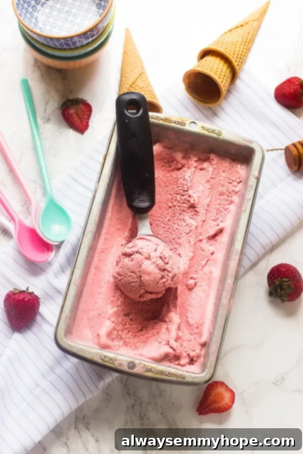 Top 15 Vegan Frozen Treats for Summer Relief 7 Strawberry coconut ice cream in a silver tub with a scoop on top.
