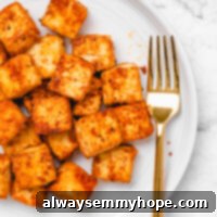 Effortless Baked Tofu for Meal Prep 2 Close-up shot of crispy seasoned tofu on a round white plate with a gold fork