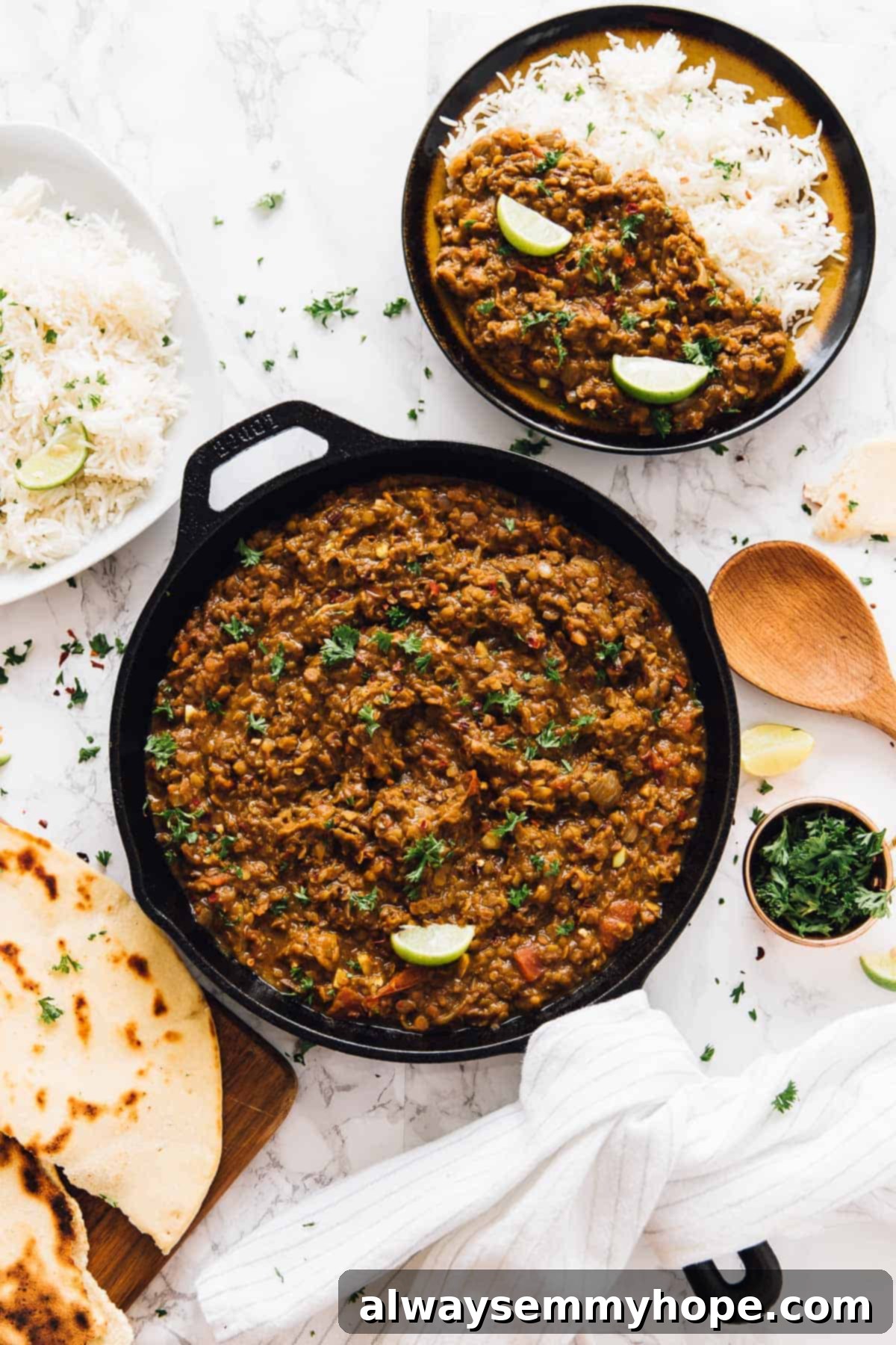 Top down view of red lentil curry served in a skillet with naan bread on the side.