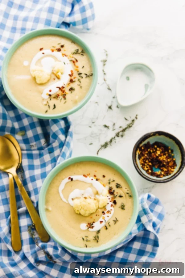 Top down view of creamy cauliflower soup served in two elegant blue bowls.