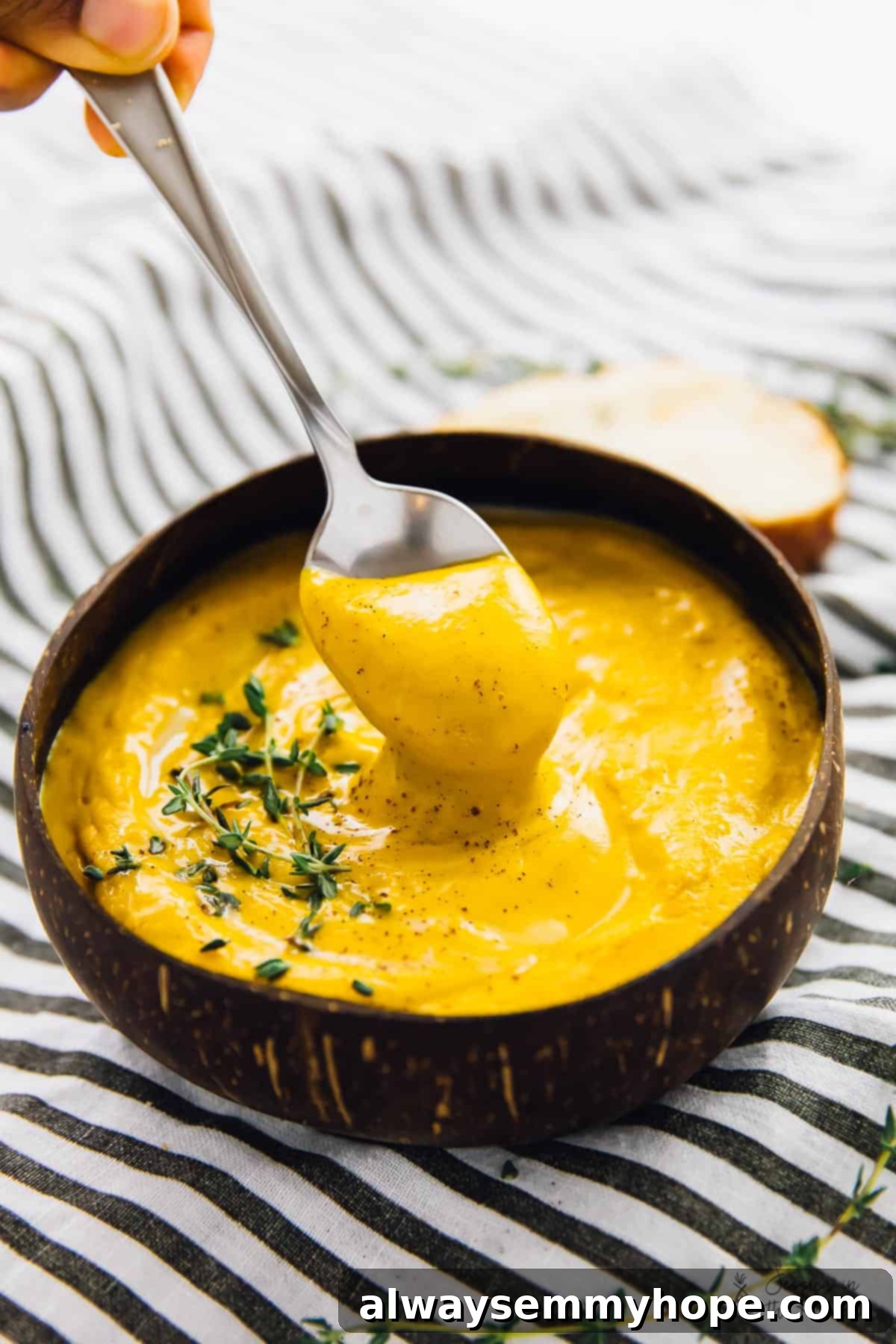 A spoon dipped into a rich, creamy bowl of roasted sweet potato soup.