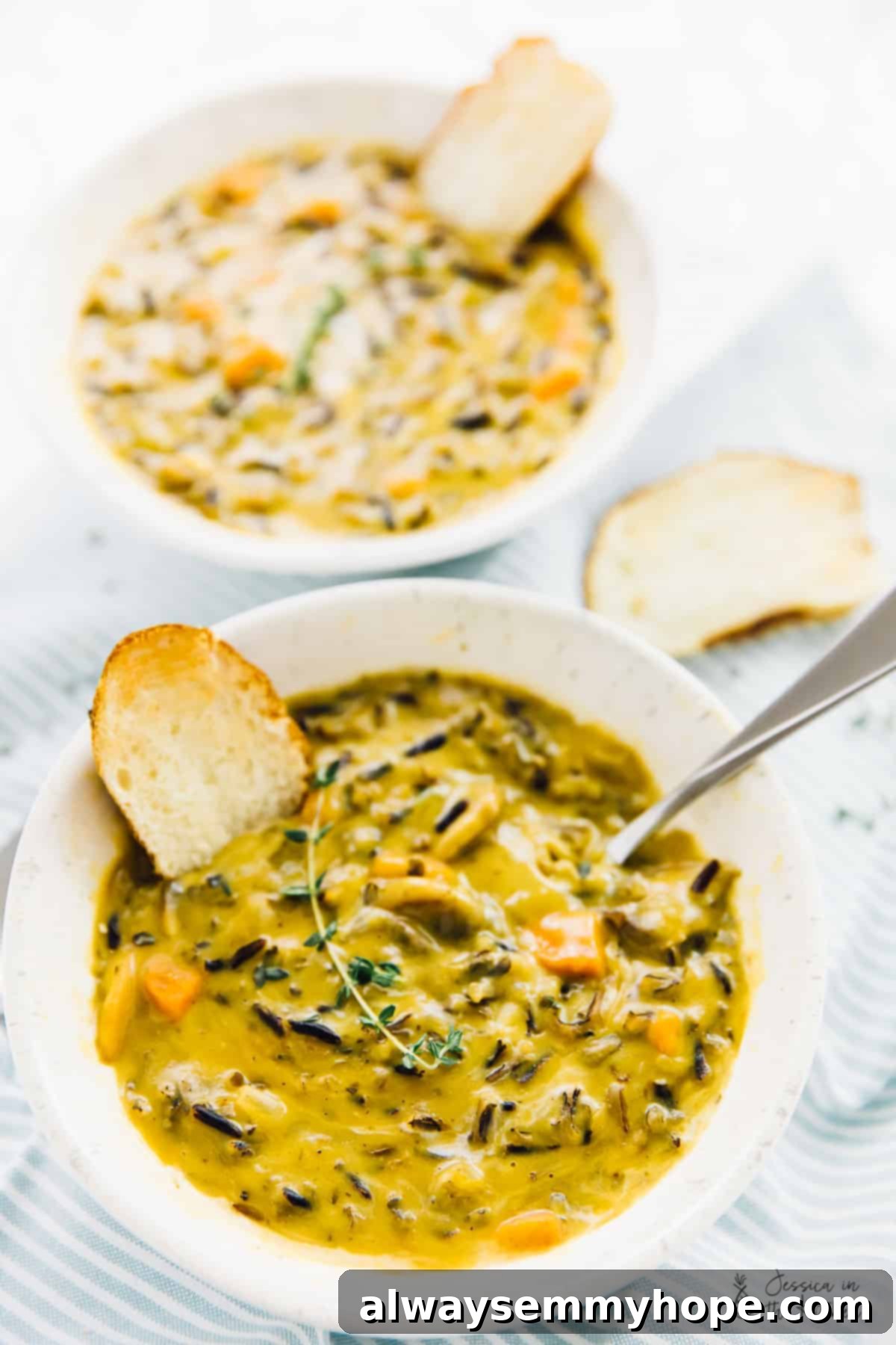 Two inviting bowls of creamy mushroom wild rice soup, garnished with fresh herbs.