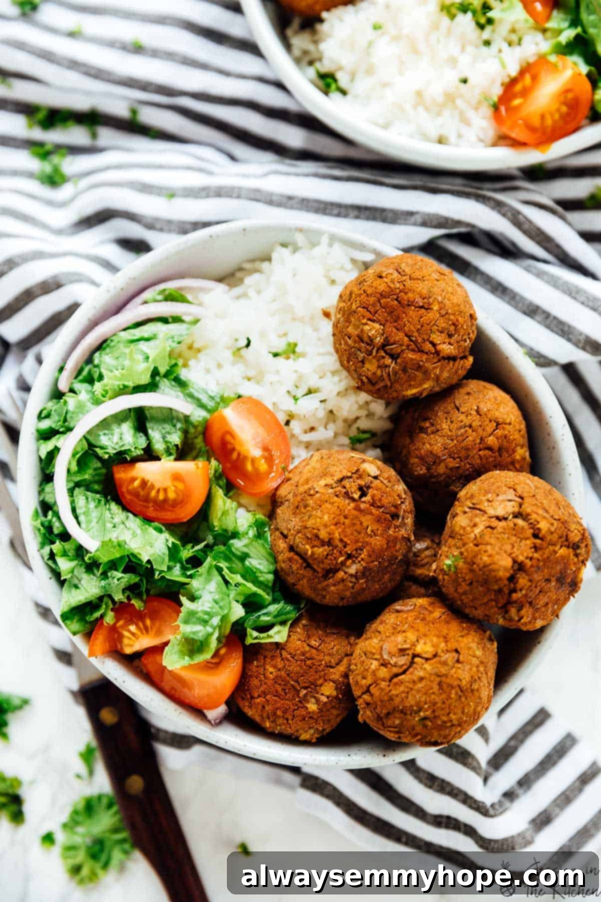 Lentil balls served with zesty rice in a bowl, accompanied by a fresh side salad.