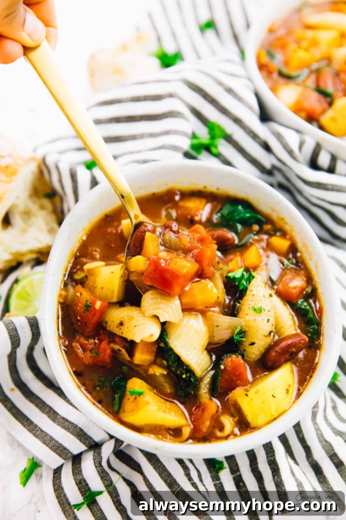 A spoon scooping out some hearty minestrone soup from a rustic bowl.