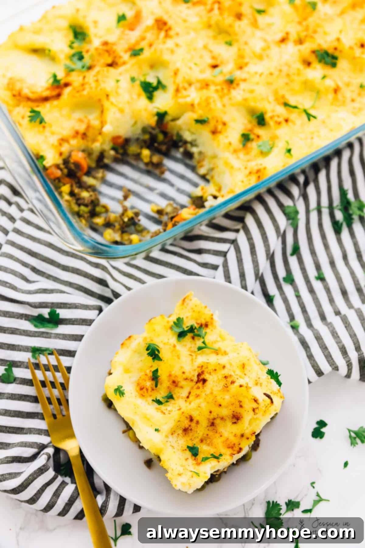 A generous portion of vegan shepherd's pie on a plate, with a baking dish in the background.