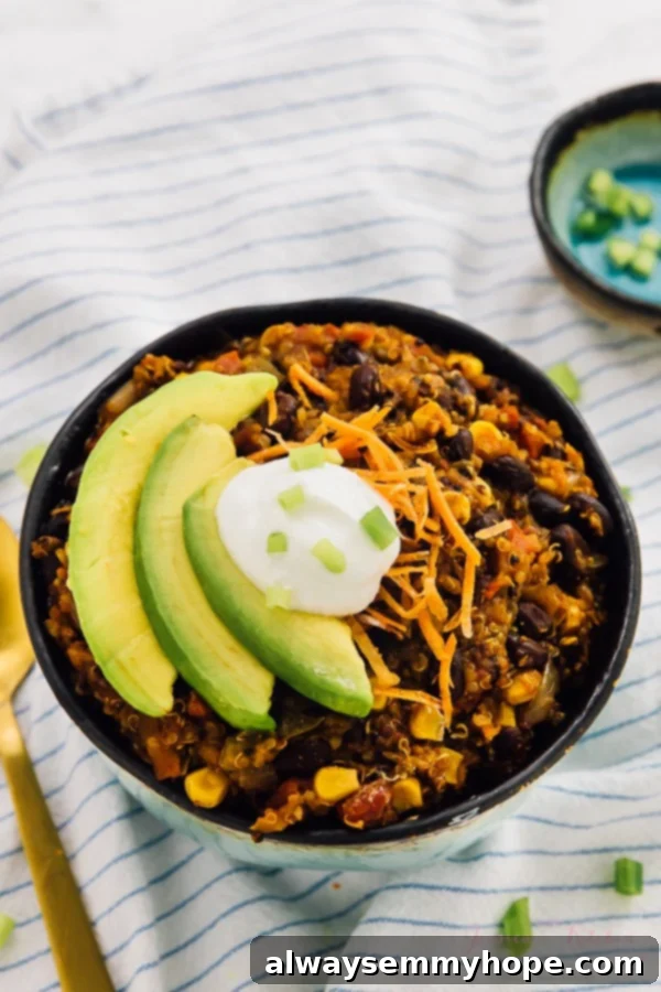 A bowl of vegan crockpot chili, generously topped with sliced avocado.