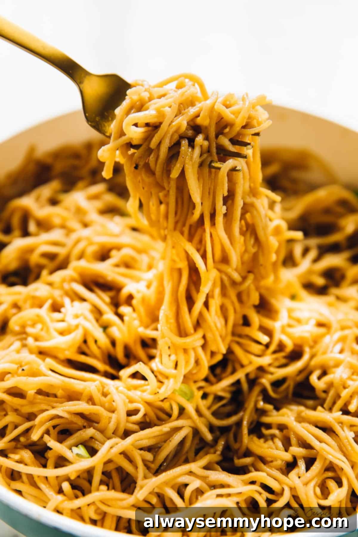 A fork pulling some sesame noodles from a beautifully plated bowl.