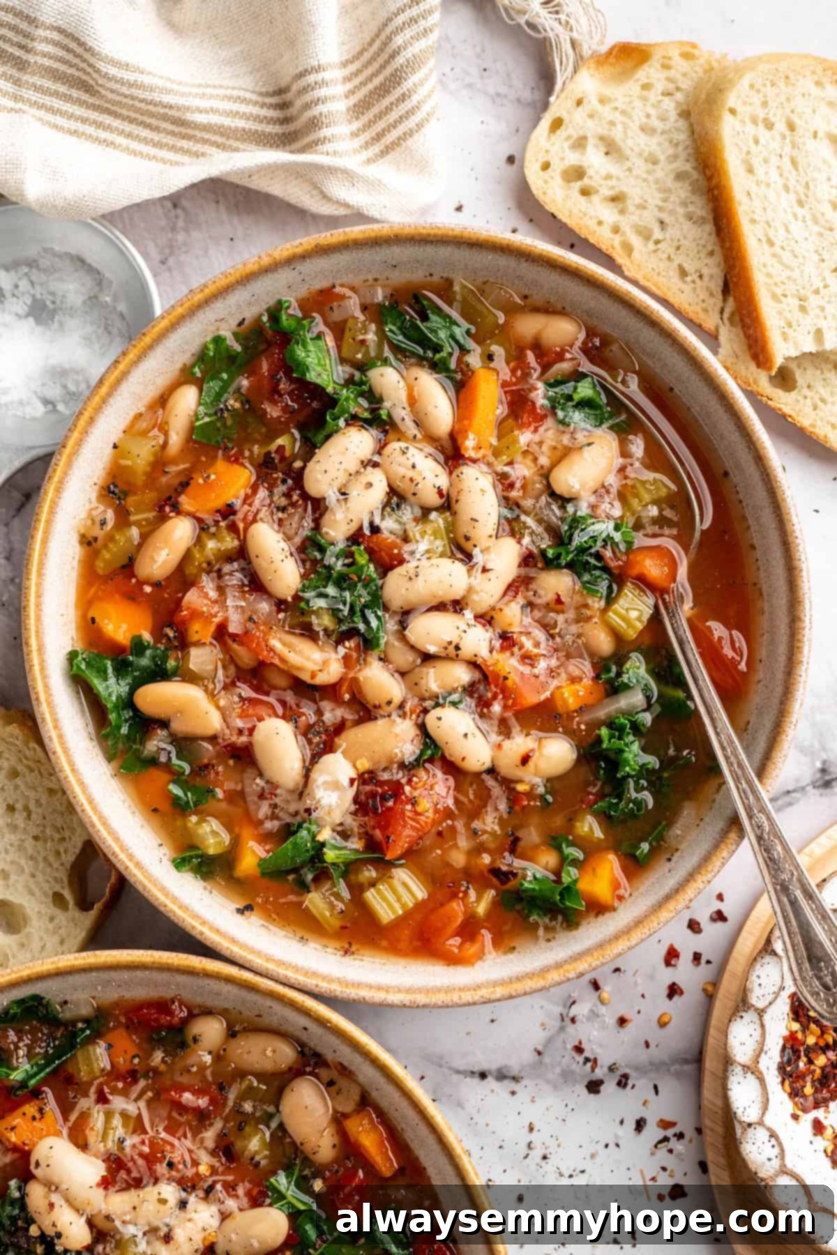 Overhead view of white bean and kale soup in bowl with spoon, ready to be enjoyed