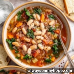 Overhead view of white bean and kale soup in bowl with spoon