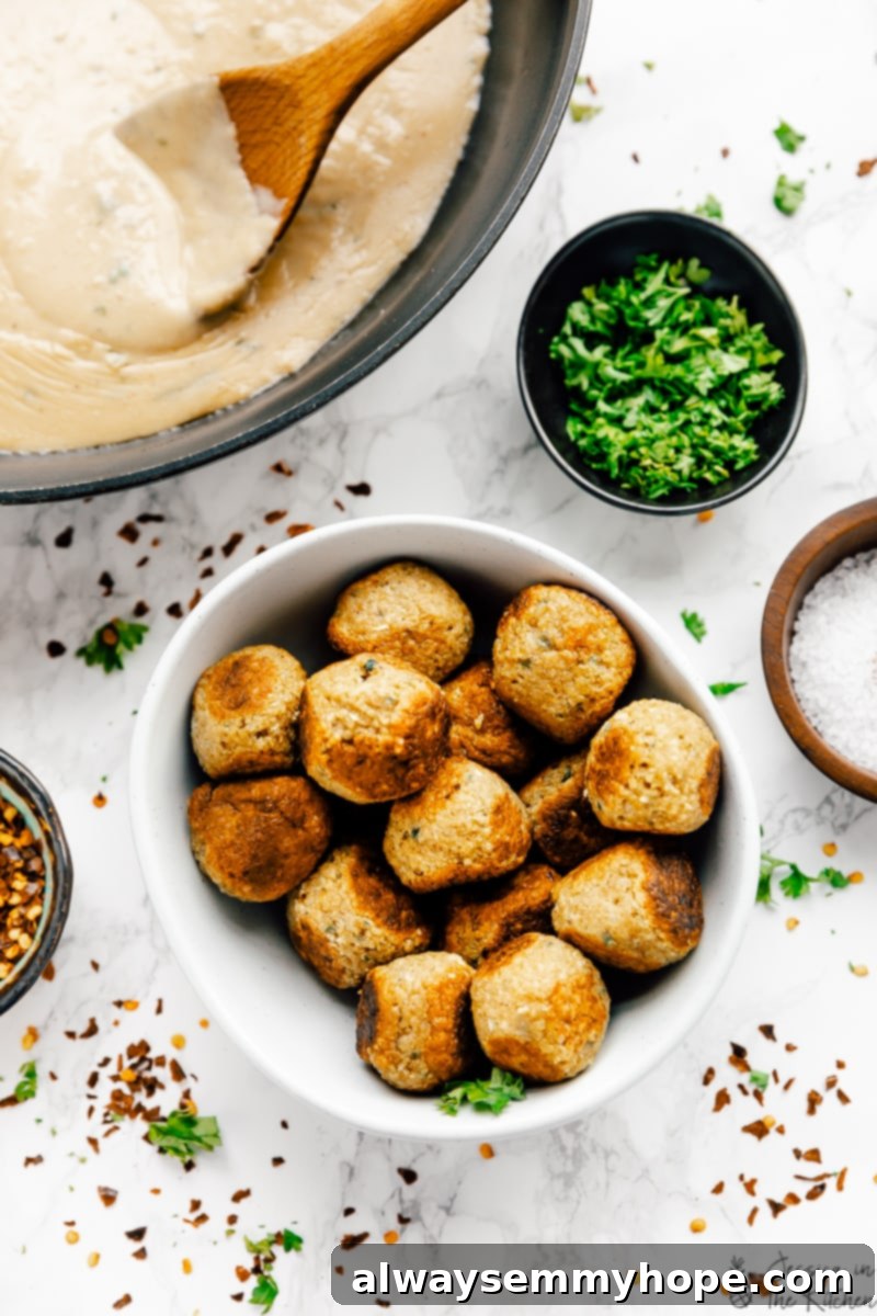Vegan meatballs in a bowl with sauce and fresh herbs, surrounded by ingredients