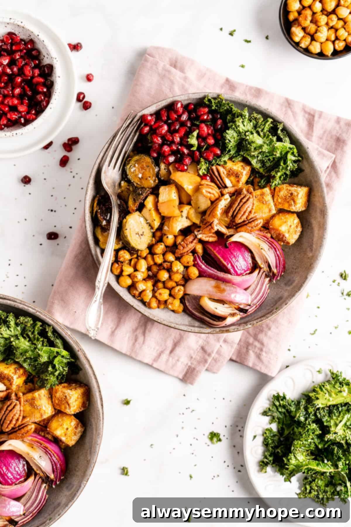 This vegan Buddha bowl is a flavor-packed meal brimming with caramelised roasted veggies, crispy chickpeas, tender baked tofu, and more! Overhead view of a vegan Buddha bowl with a fork nestled into its colorful contents, resting on a pink cloth napkin.