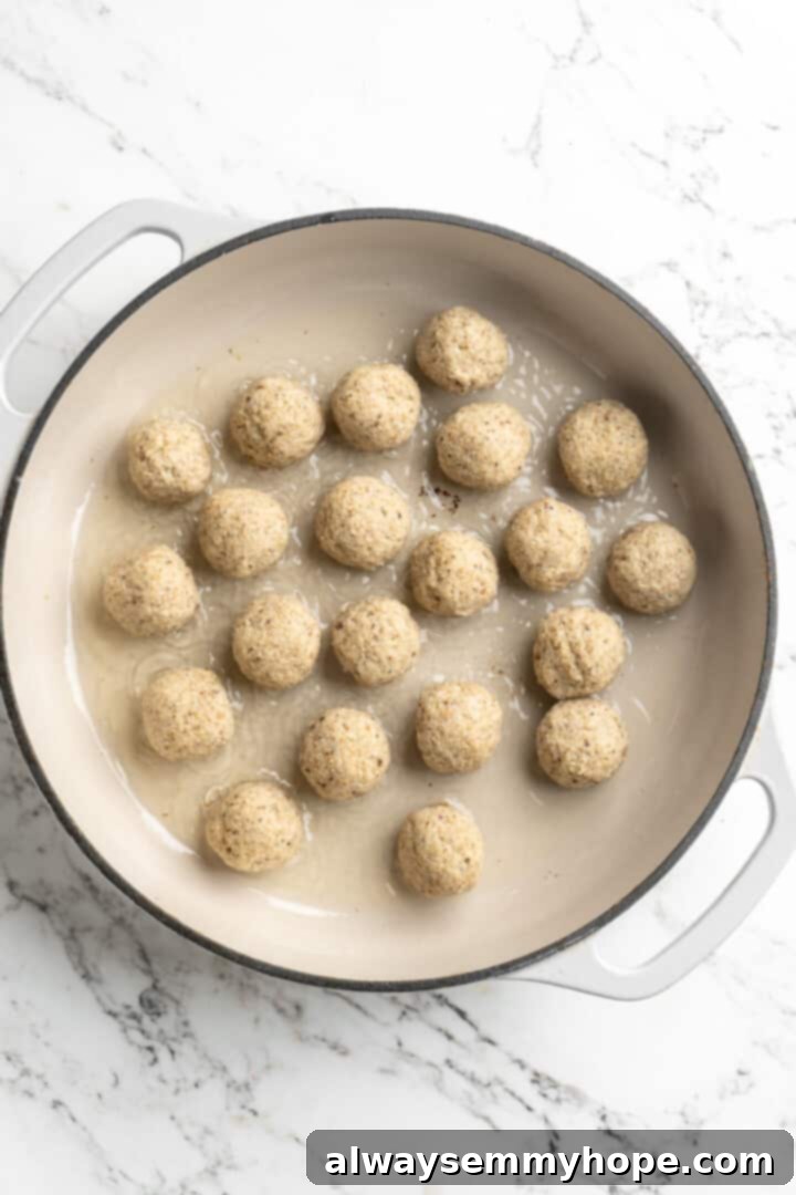 Overhead view of uncooked vegan meatballs added to pan of oil