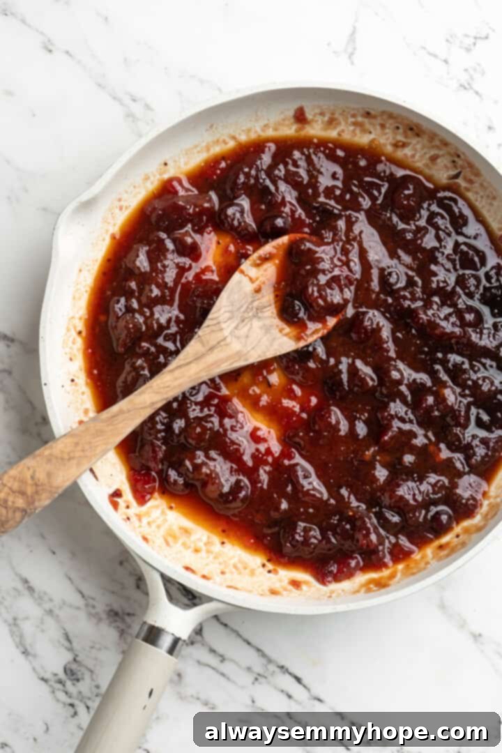 Overhead view of cranberry sauce in skillet with wooden spoon