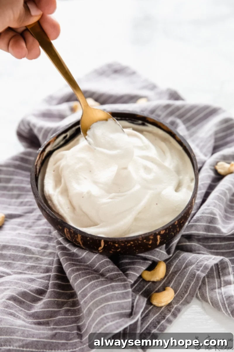 Kaju Kreması Tarifi: Süt Ürünü İçermeyen Enfes Vegan Alternatif 2 A bowl of silky smooth cashew cream with a spoon lifting some out, ready for use as a dairy-free substitute.