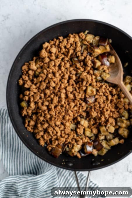 Vegan meat crumbles and eggplant in a pan.