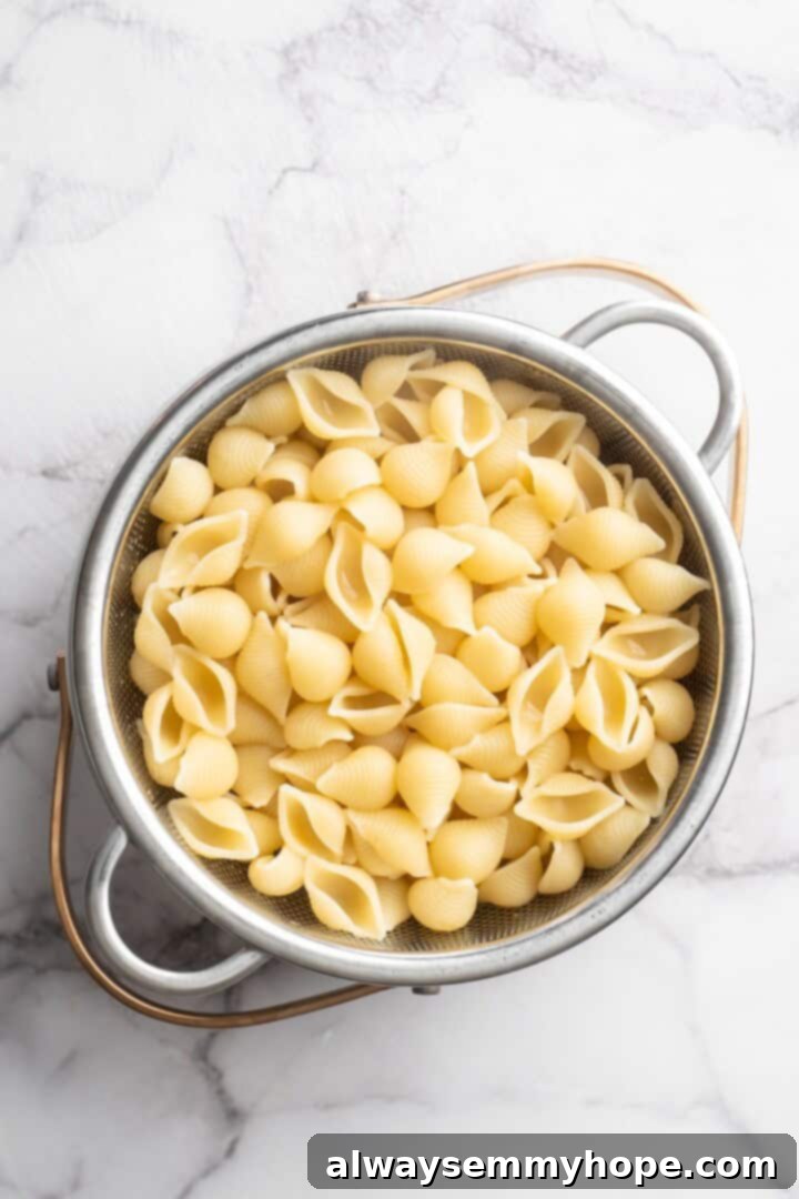 Overhead view of perfectly cooked pasta shells in a colander, ready to be added to the sauce.