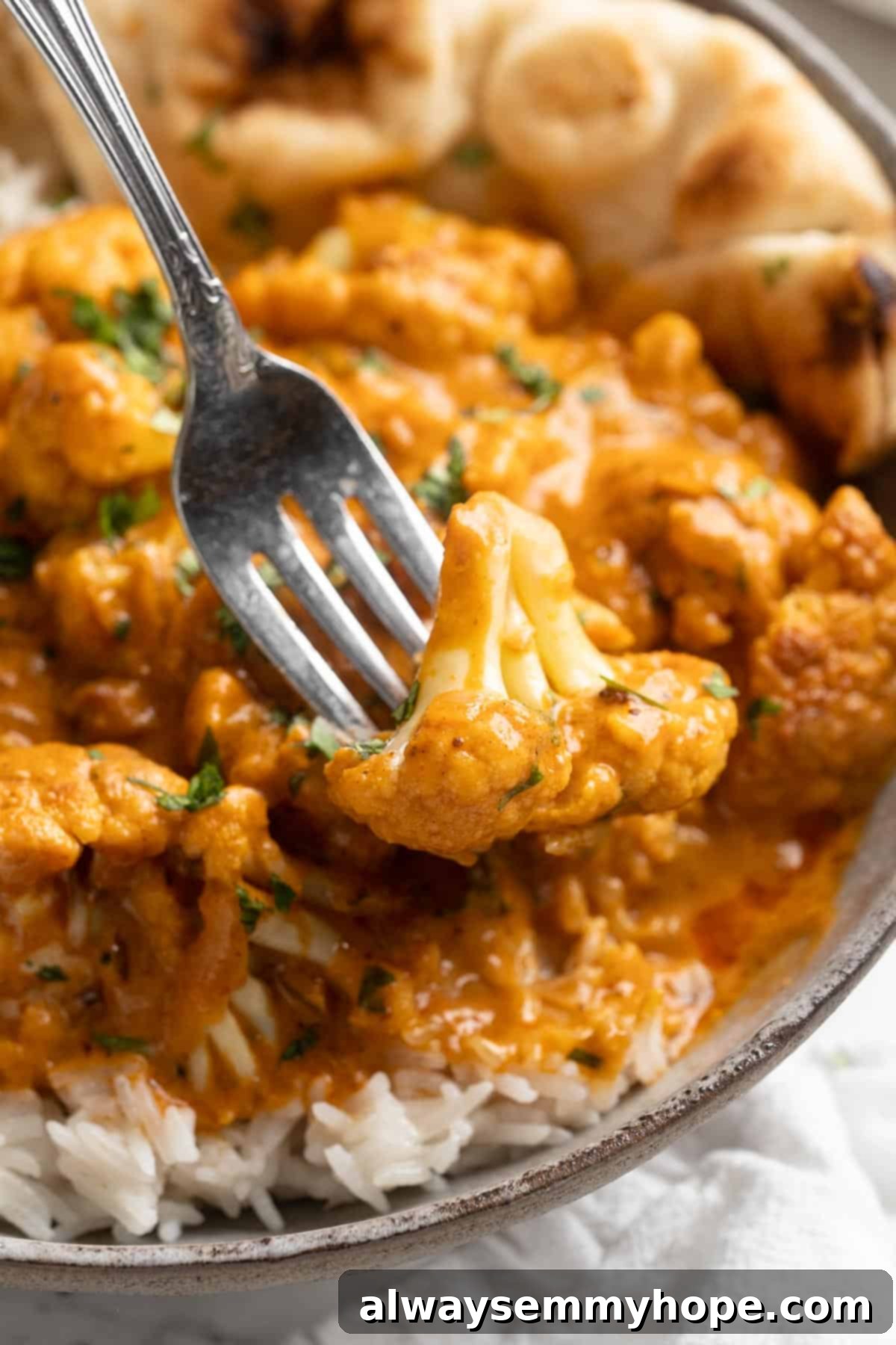 This vegan butter cauliflower starts by marinating the cauliflower in coconut and spices, making it extra delicious. Better than takeout! Butter cauliflower floret on fork