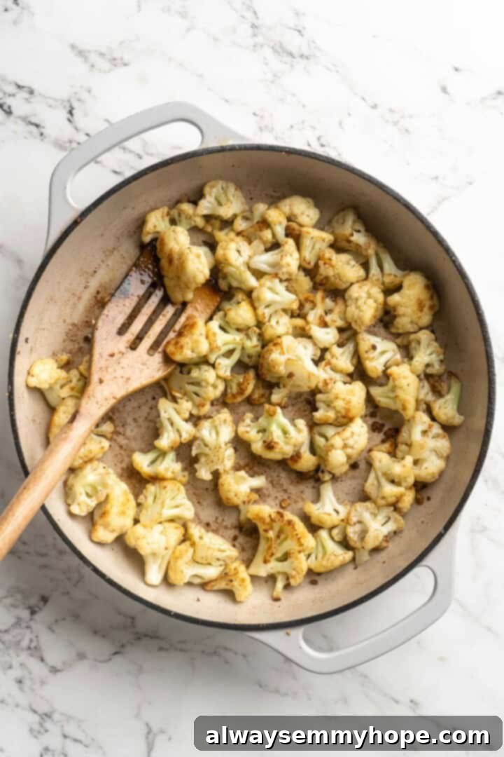 This vegan butter cauliflower starts by marinating the cauliflower in coconut and spices, making it extra delicious. Better than takeout! Overhead view of cauliflower in pan