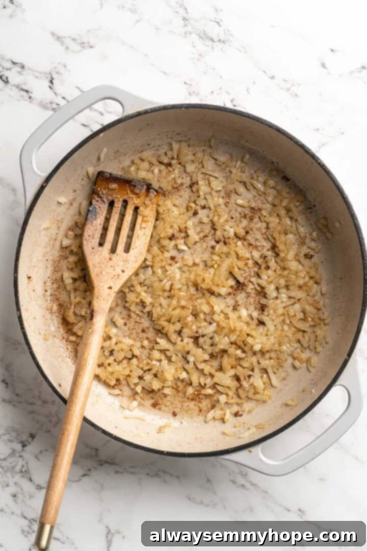 This vegan butter cauliflower starts by marinating the cauliflower in coconut and spices, making it extra delicious. Better than takeout! Overhead view of sauteed onions in pan