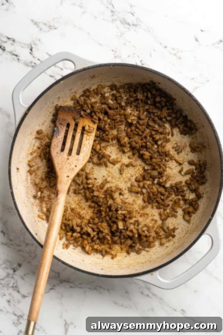 This vegan butter cauliflower starts by marinating the cauliflower in coconut and spices, making it extra delicious. Better than takeout! Overhead view of onion and spices in pan