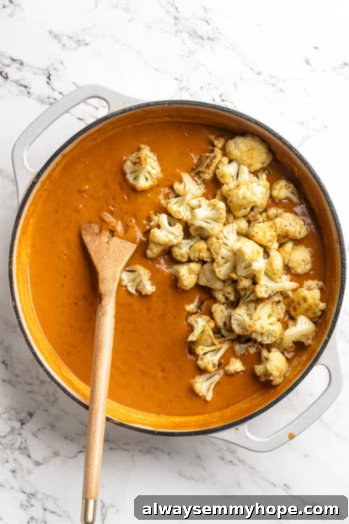 This vegan butter cauliflower starts by marinating the cauliflower in coconut and spices, making it extra delicious. Better than takeout! Cauliflower added to pan of vegan butter sauce