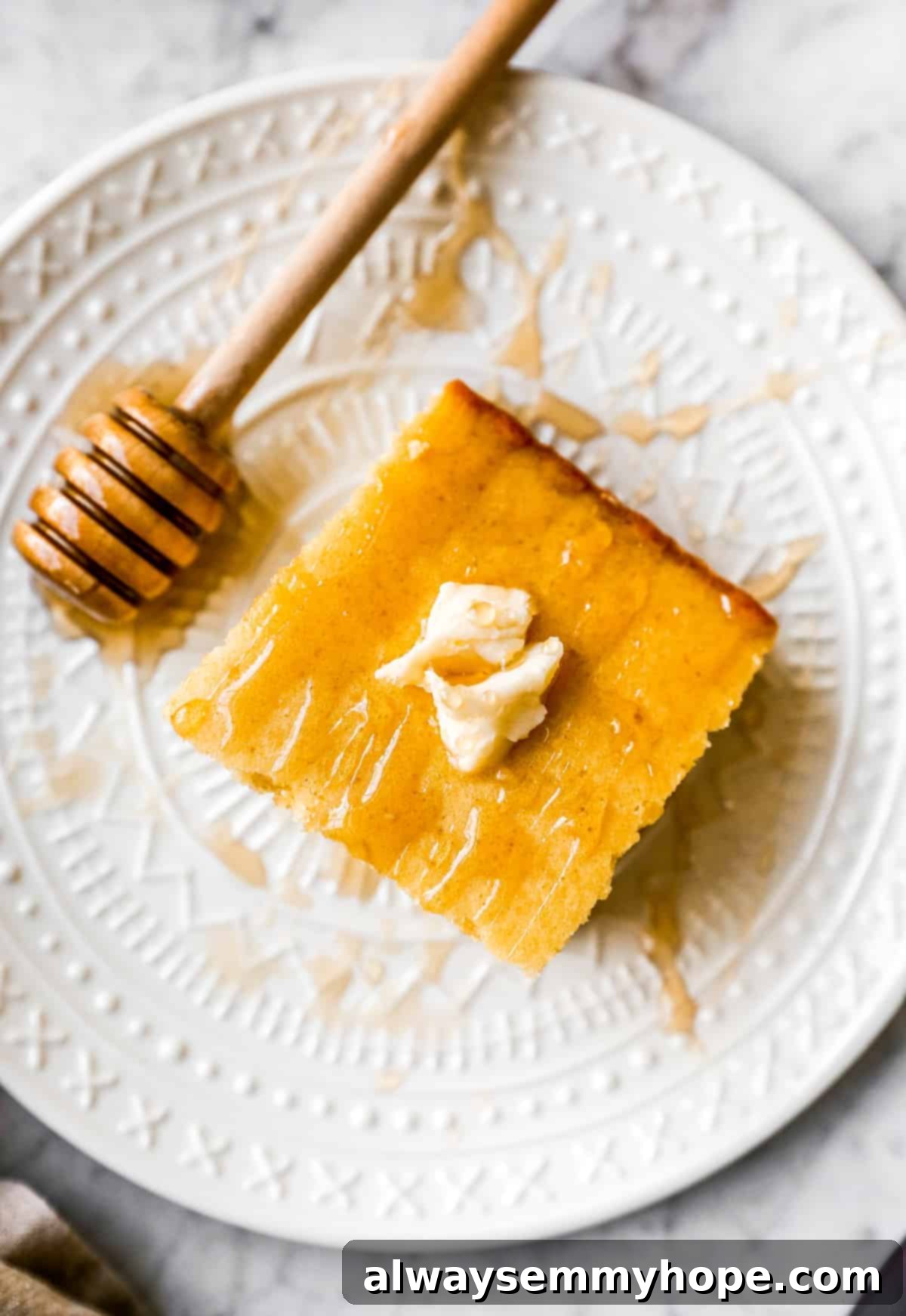 A single golden slice of vegan cornbread on a white plate, showcasing its fluffy texture.