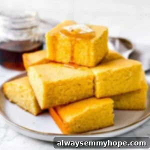 cornbread muffins in a stack with maple syrup drizzled on top and a pat of butter