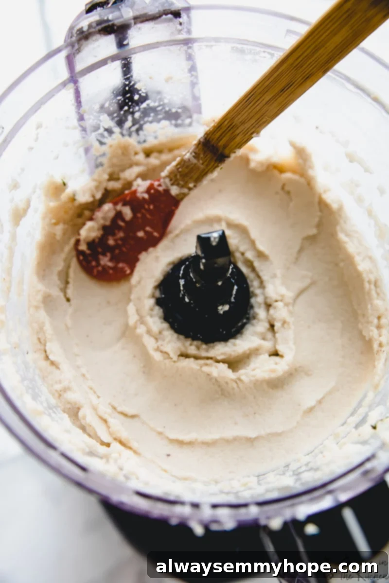 Stirring cauliflower mash in a food processor, showing its creamy texture.