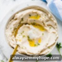 Top down view of mashed cauliflower in a bowl with a spoon.