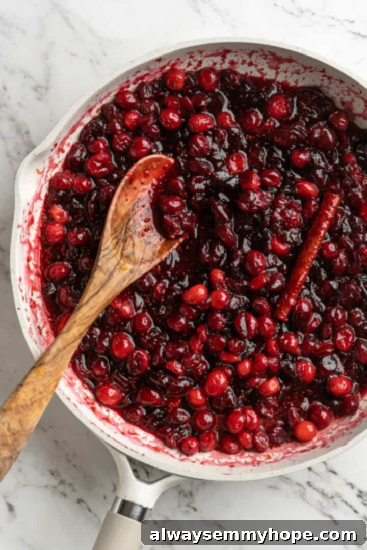 Overhead view of cranberry orange sauce in pan with wooden spoon